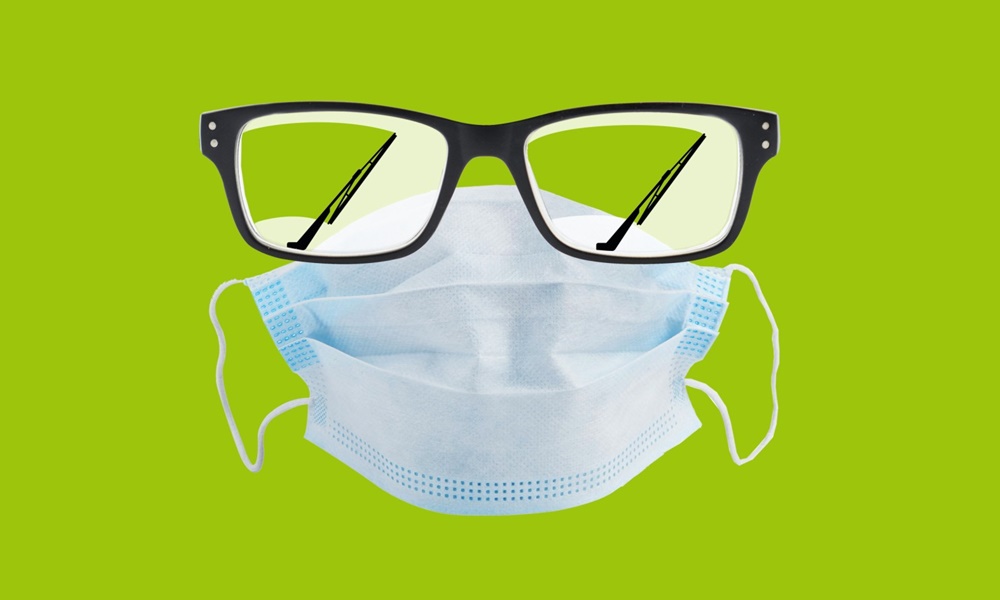Mund-Nasen-Schutzmaske gegen Covid-19 mit Brille vor grünem Hintergrund